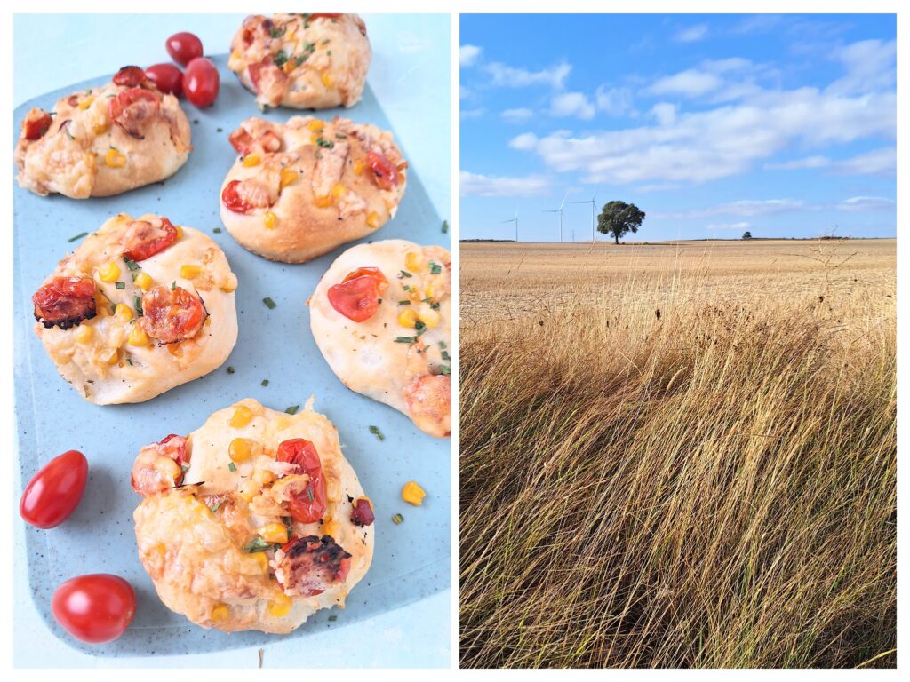 Selbstgemachte Pizzerinki mit Mais und Tomate und rechts ein einsamer Baum im Feld.